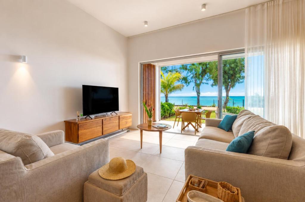 a living room with a couch and a flat screen tv at Beachfront Apartment with Garden & Direct Beach Access in Grande Gaube