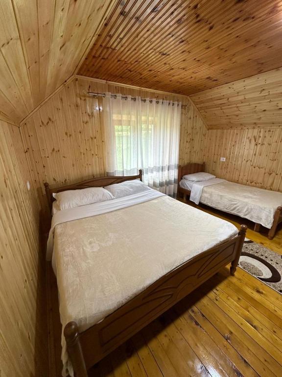 a bedroom with two beds in a wooden room at Bujtina Turkaj in Nikshi