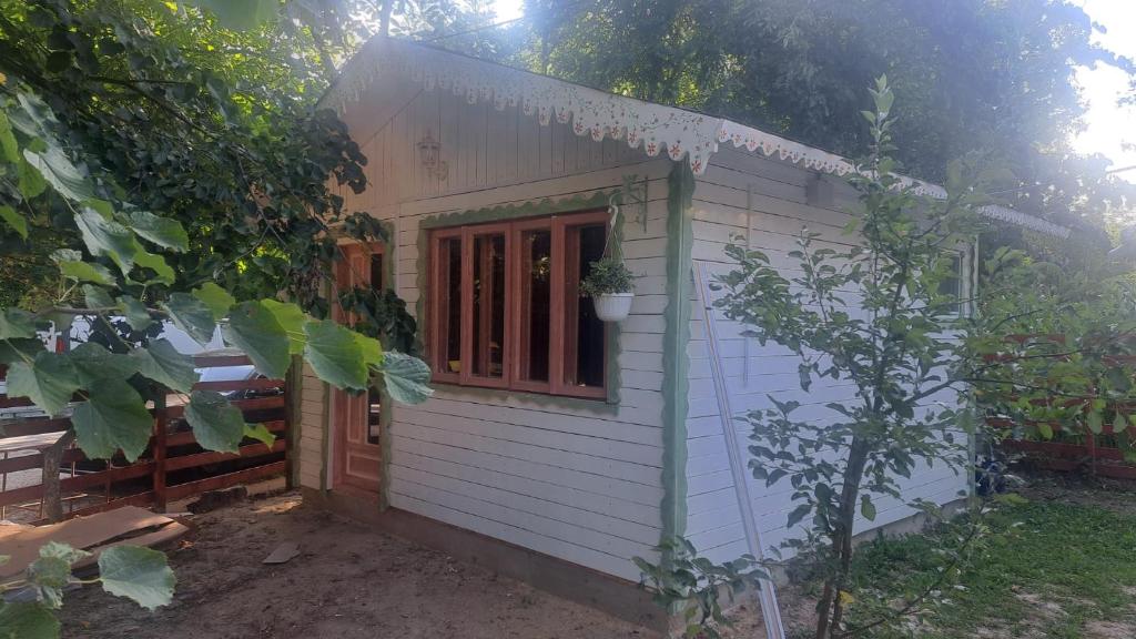 a small white house with a red door at Căsuța Veselă in Tătuleşti