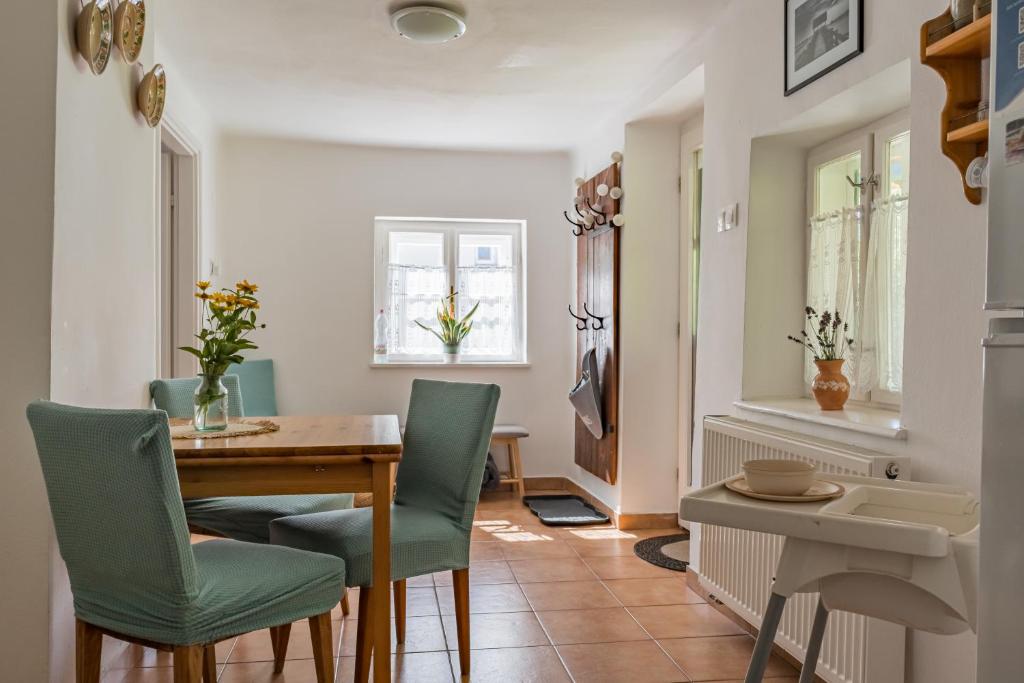 a dining room with a wooden table and green chairs at Hetedhét Vendégház in Mórahalom