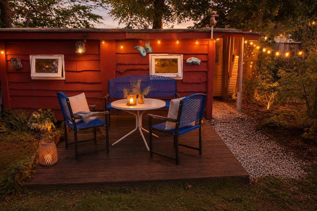 eine Terrasse mit Tisch, Stühlen und Beleuchtung in der Unterkunft Spa-Francorchamps Forest Lodge in Amel