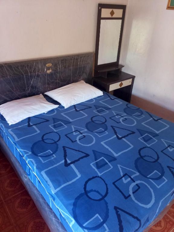 a bed in a room with a blue blanket on it at Chepclean in Kelimutu