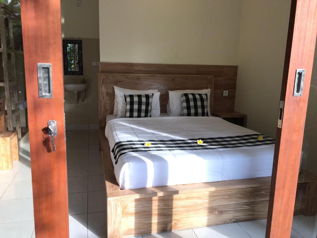 a bedroom with a large bed with a wooden headboard at Nataliya Homestay in Ubud