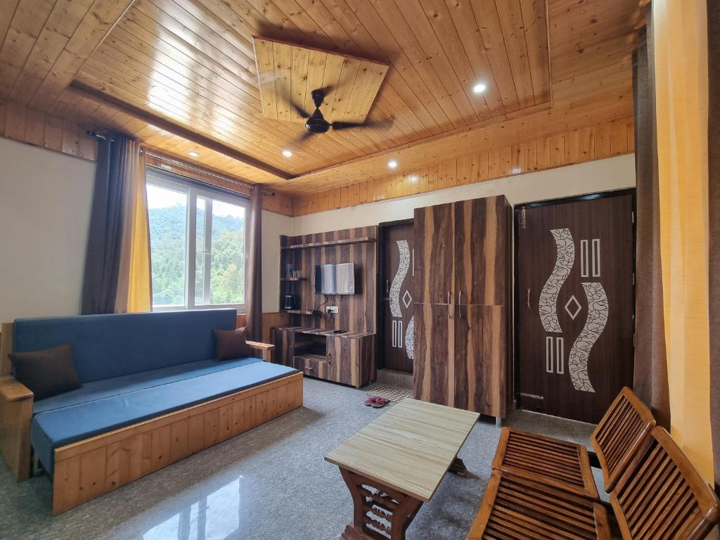 a living room with a blue couch and a table at Hotel Rajinder Prasth in Dalhousie
