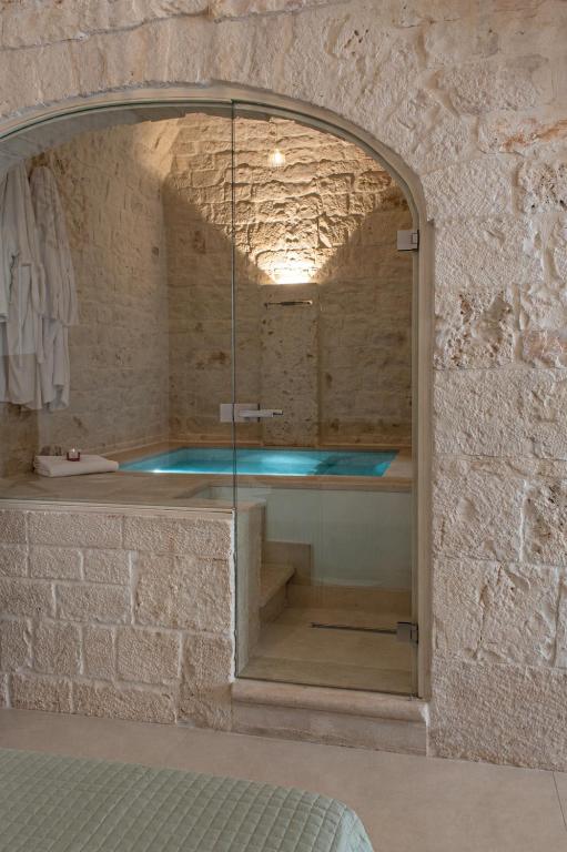 a shower in a stone wall with a glass enclosure at Aqua Suite - Stone Spa - A Few Minutes from Polignano, Monopoli & Alberobello in Castellana Grotte