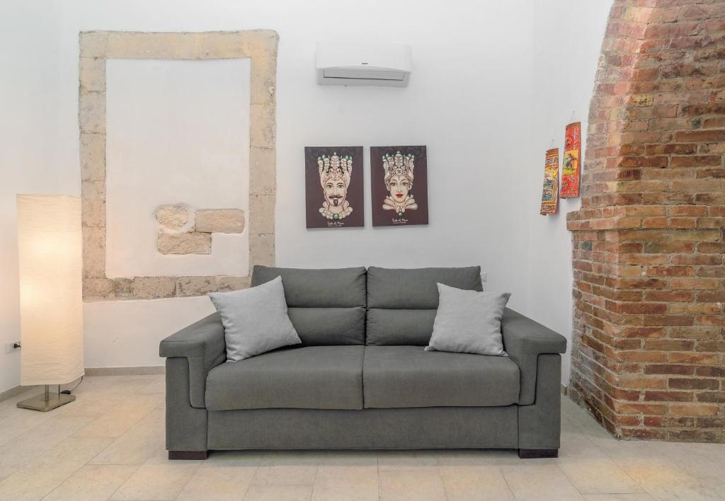 a couch in a living room with paintings on the wall at Atena Ortigia in Syracuse