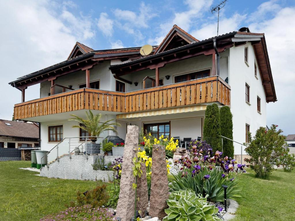 a house with a balcony and flowers in the yard at Haus Baden in Hagnau