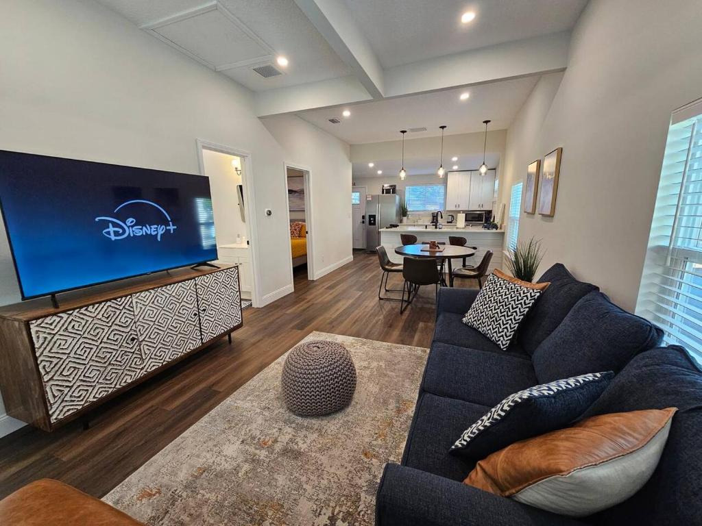 a living room with a blue couch and a large tv at Steps to Trolley Stop 11 Renovated Home with Free EV Station in St. Augustine