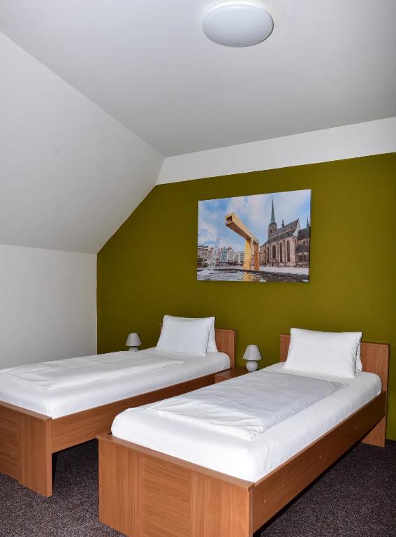 two beds in a room with a green wall at Apartmány U Gigantu in Pilsen