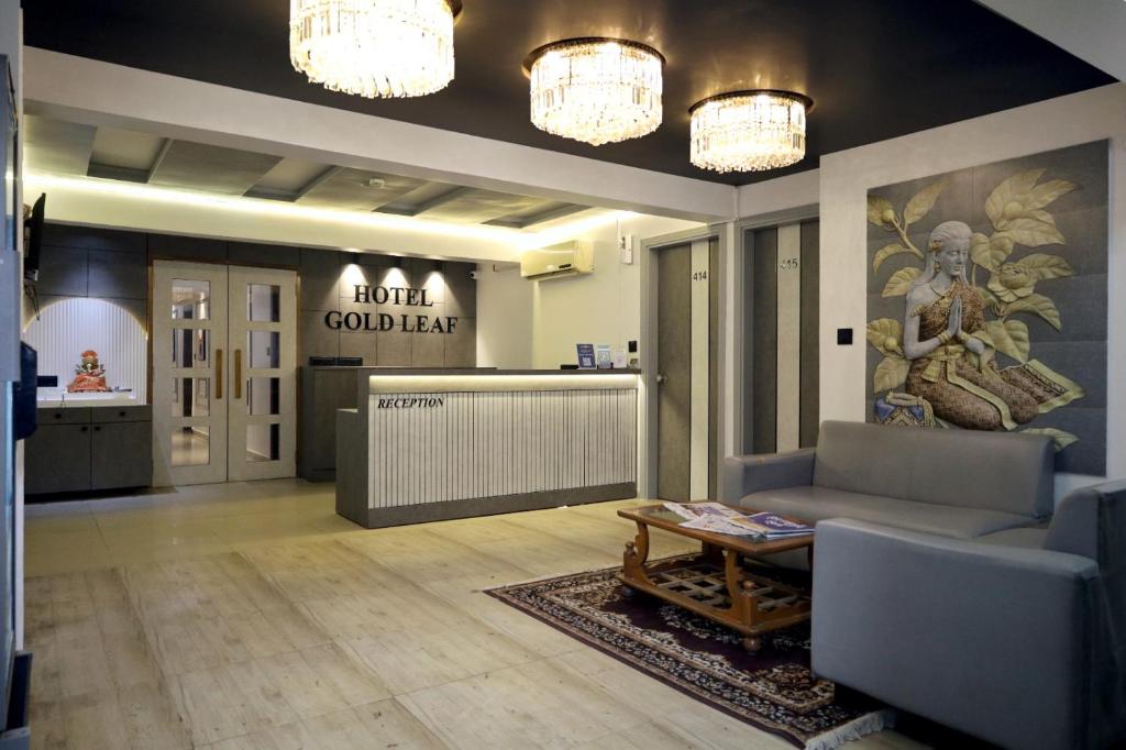 a lobby with a couch and a table and chandeliers at HOTEL GOLD LEAF in Ahmedabad