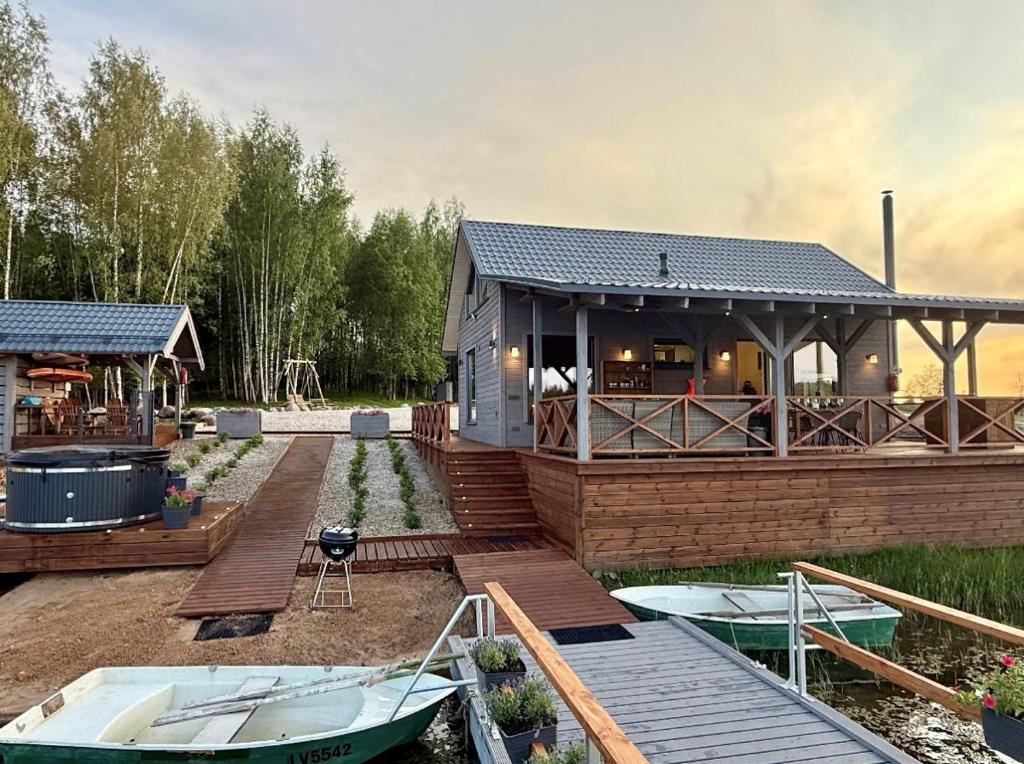 a house with a deck and a boat on the water at Rūdupji Anna in Kalniena