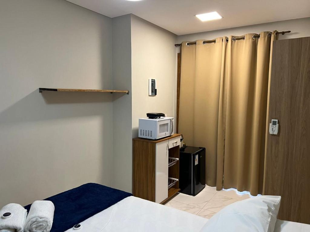 a hotel room with a bed and a microwave at Studio-type apartment in Praia do Forte in Mata de Sao Joao