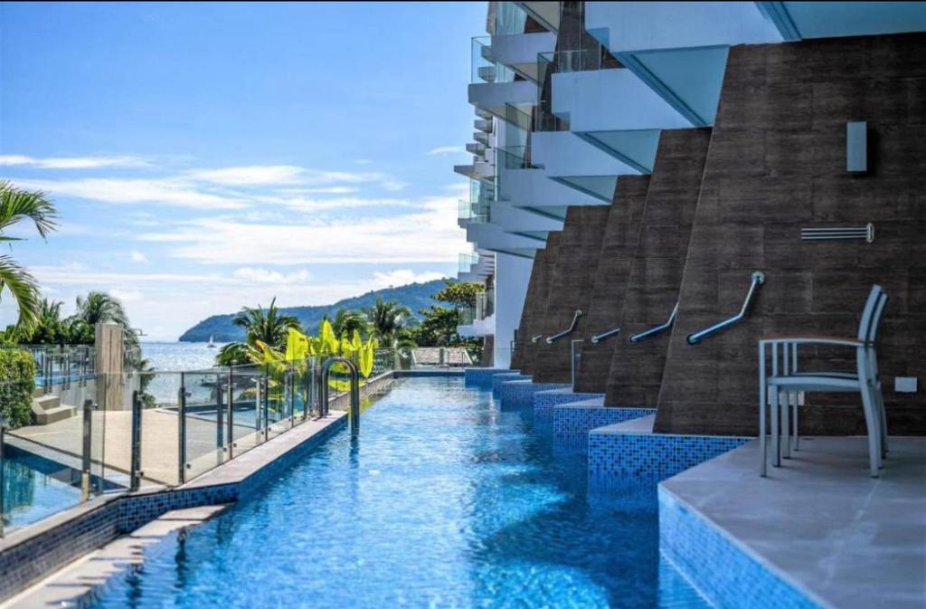 a swimming pool with a chair next to a building at Beachfront A405 Seaview Studio Rawai Phuket in Ban Saiyuan (1)