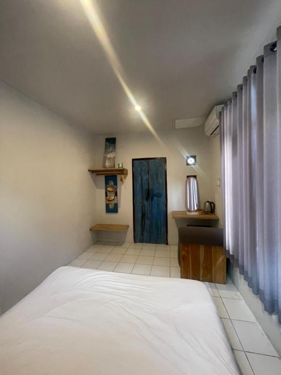 a bedroom with a large bed and a blue door at Pondok Gopi Room in Cemagi
