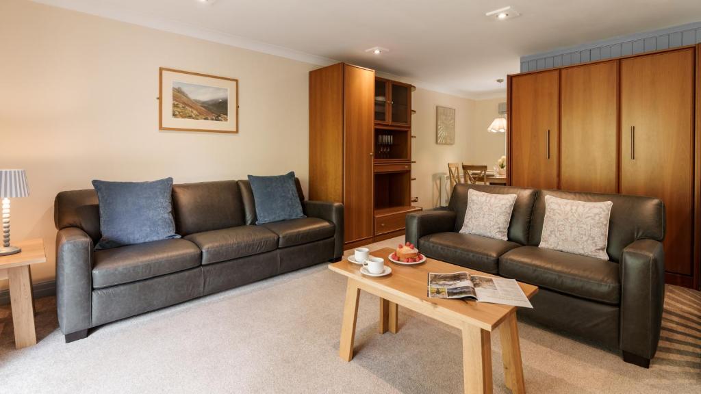 a living room with two leather couches and a coffee table at Dog Friendly Lakeland Cottage At Windermere Marina Village in Bowness-on-Windermere