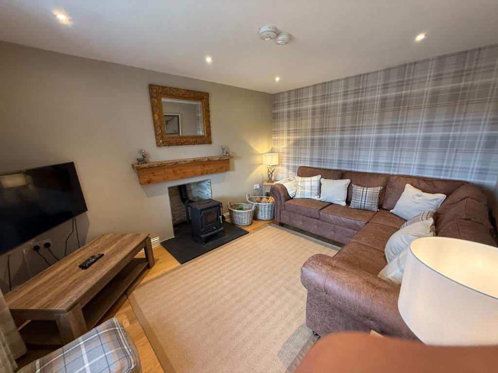 a living room with a couch and a fireplace at Alt-Na-Slat Cottage in Invergarry