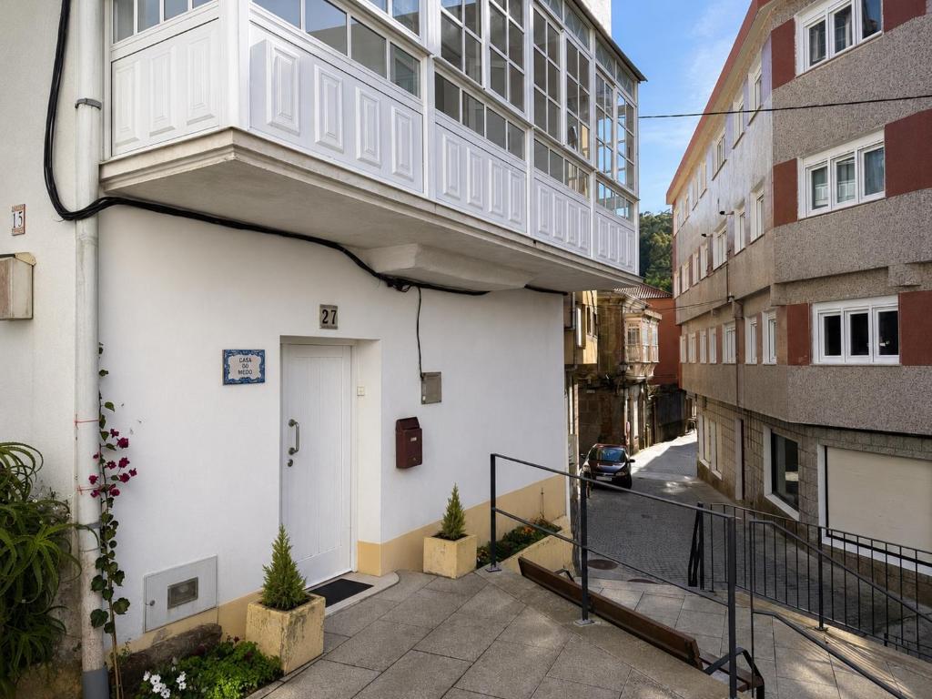 a white building with a balcony on the side of it at Casa do medio in Corcubión
