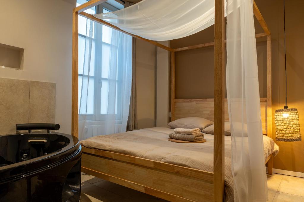 a bedroom with a canopy bed and a tub at Love Room avec Jacuzzi - Le cocon caché in Bressuire