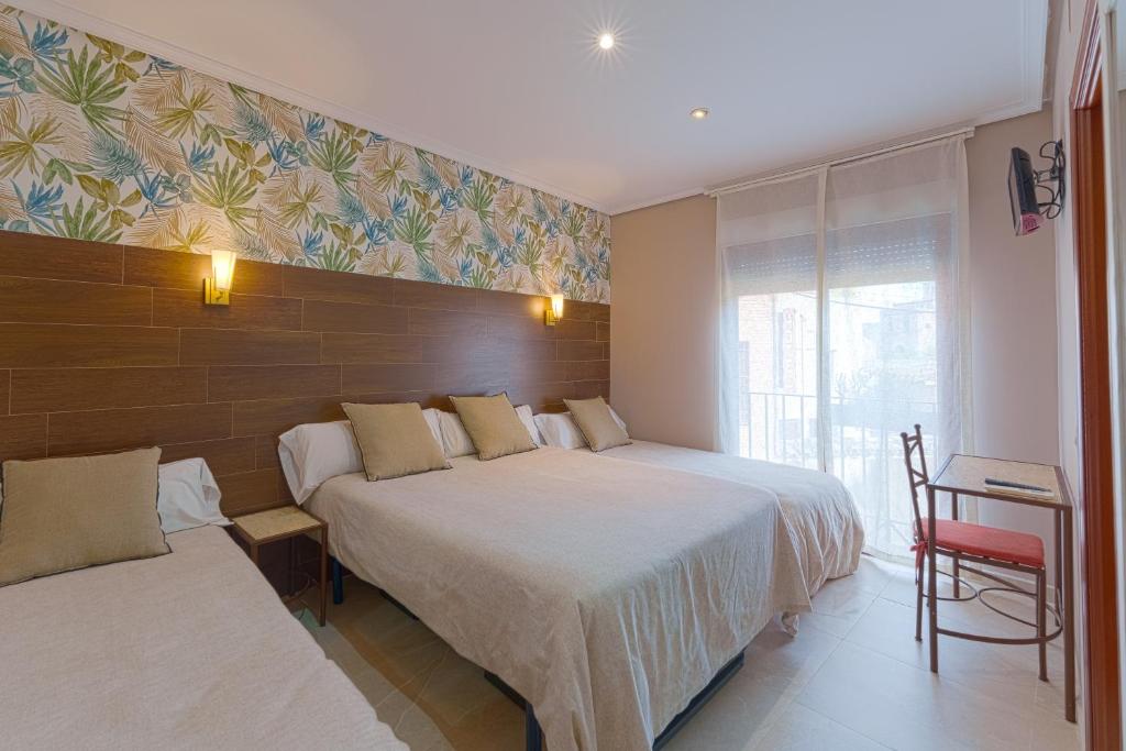 a hotel room with two beds and a chair at Hostal Sol in Toledo