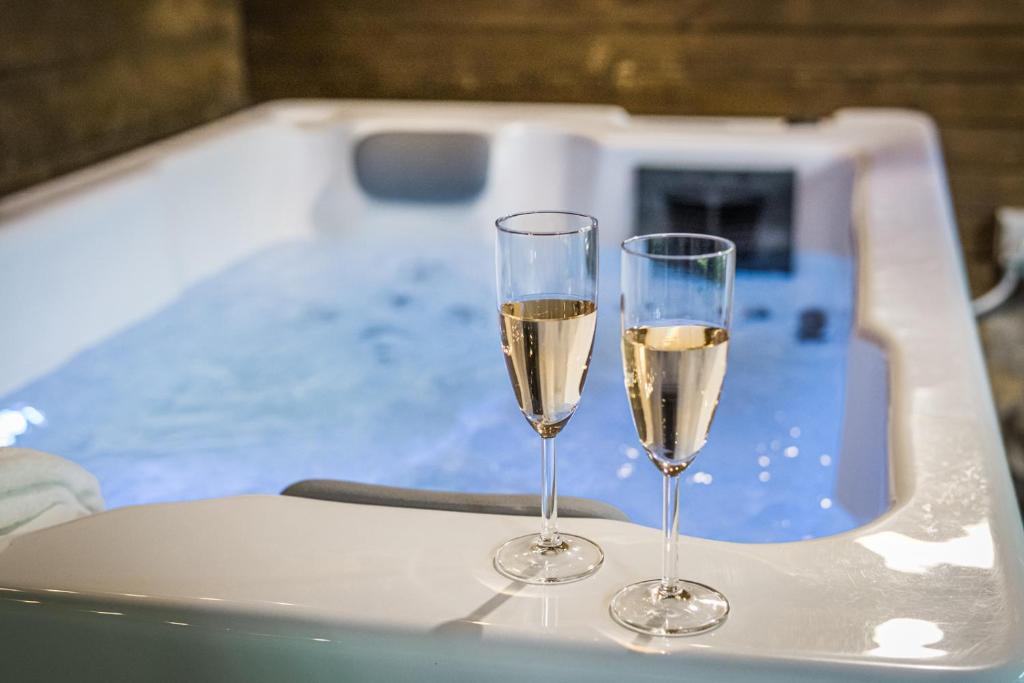 two glasses of champagne sitting on a table next to a tub at Mátra Boutique in Mátraszentimre