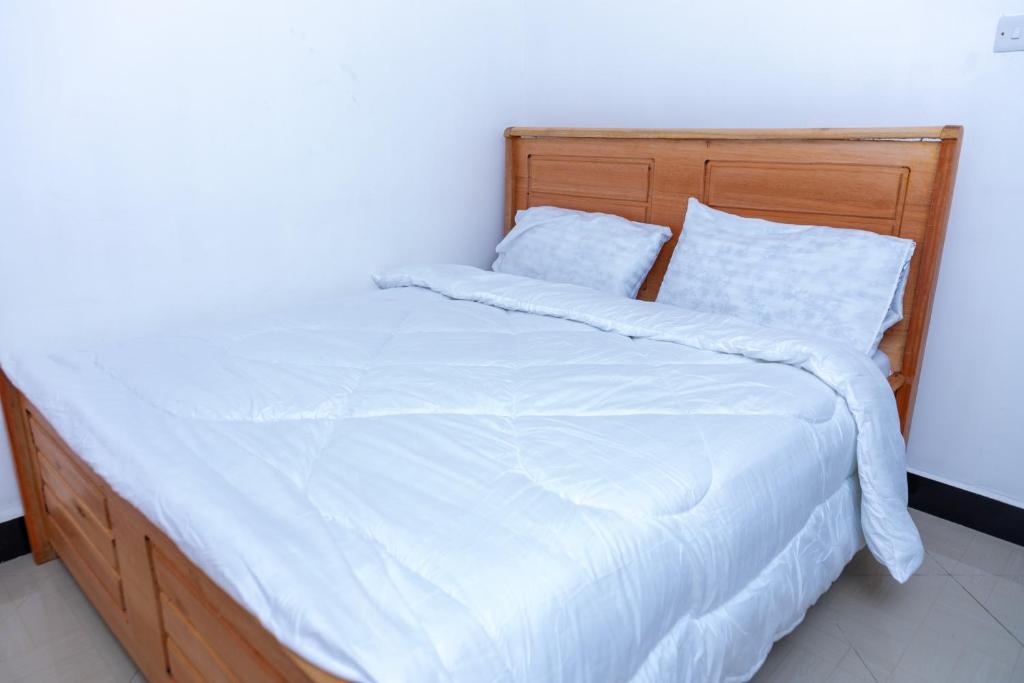 a bed with white sheets and pillows in a room at La casa Cottage in Iringa