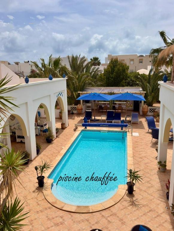 a large swimming pool with blue chairs and umbrellas at Chambre d'hôtes, Dar l'air du temps in Aghīr
