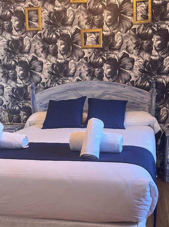 a bed with blue pillows and a wall with flowers at LA MAR SALADA in Lastres