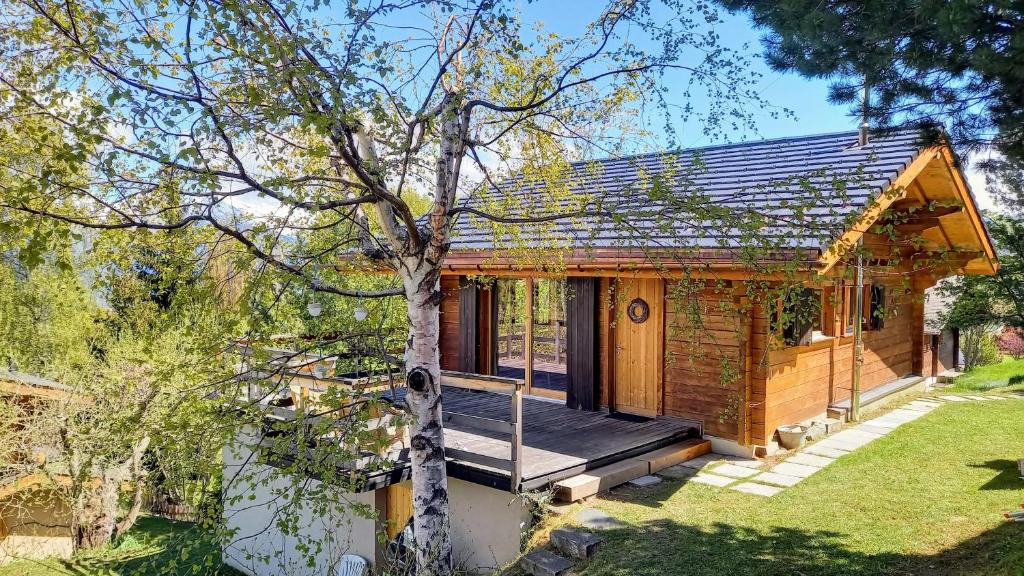 a tiny house with a porch and a tree at Chalet AS des Pics in Nendaz