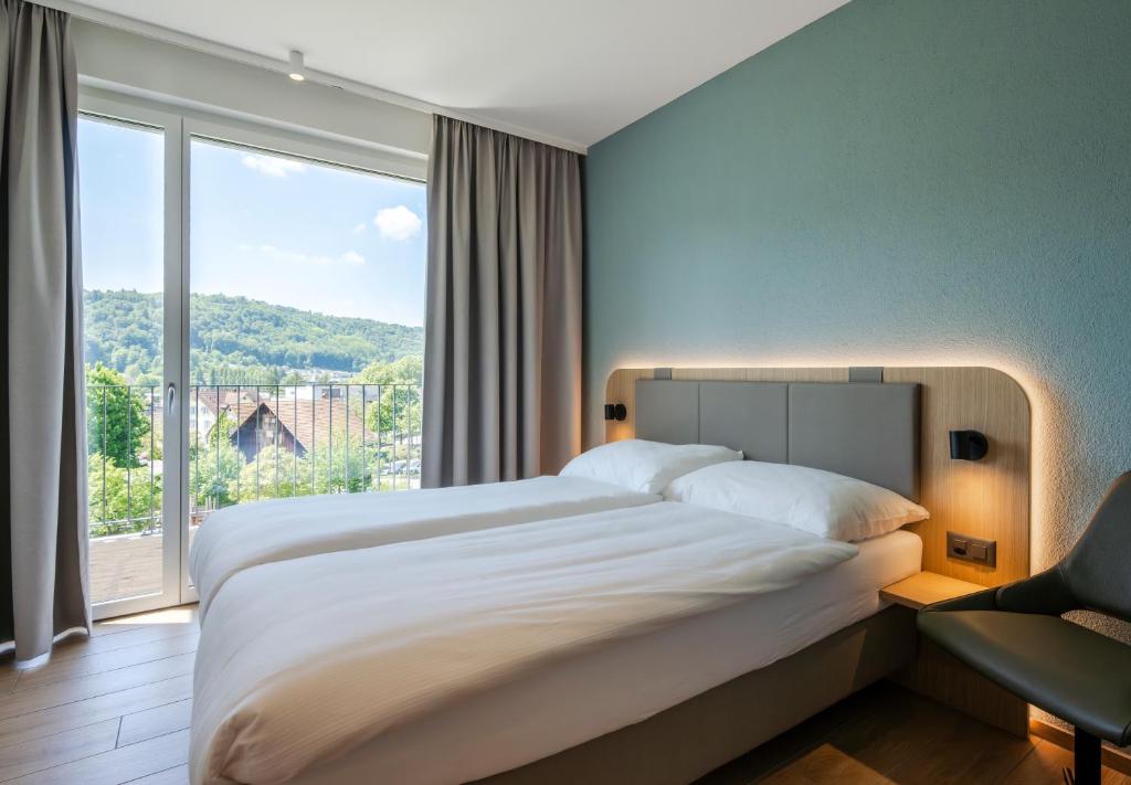 a bedroom with a large bed and a large window at stay flex Hotel & Apartment in Hertenstein