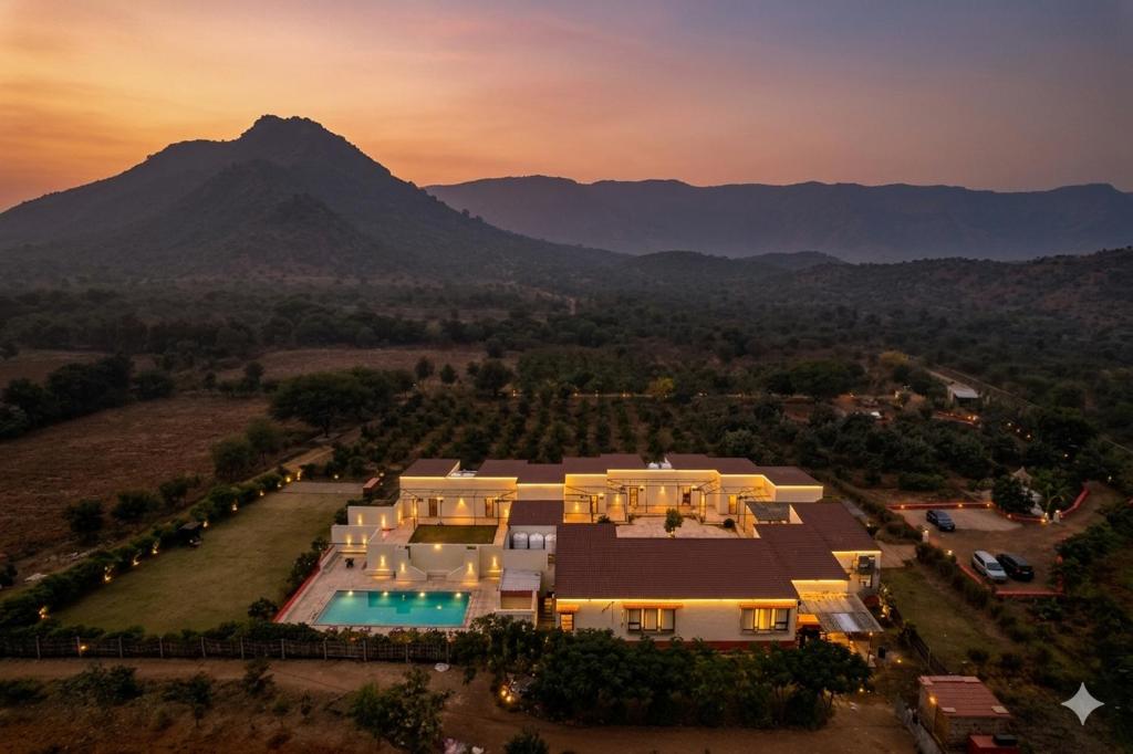an aerial view of a house with a mountain in the background at Guldaar Sariska - A Luxury Forest Retreat in Tehla