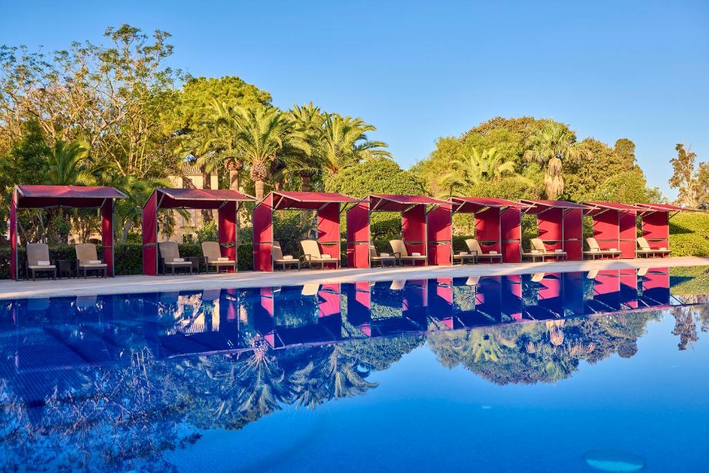 a pool at a resort with chairs and trees at Son Julia Country House & Spa in Llucmajor