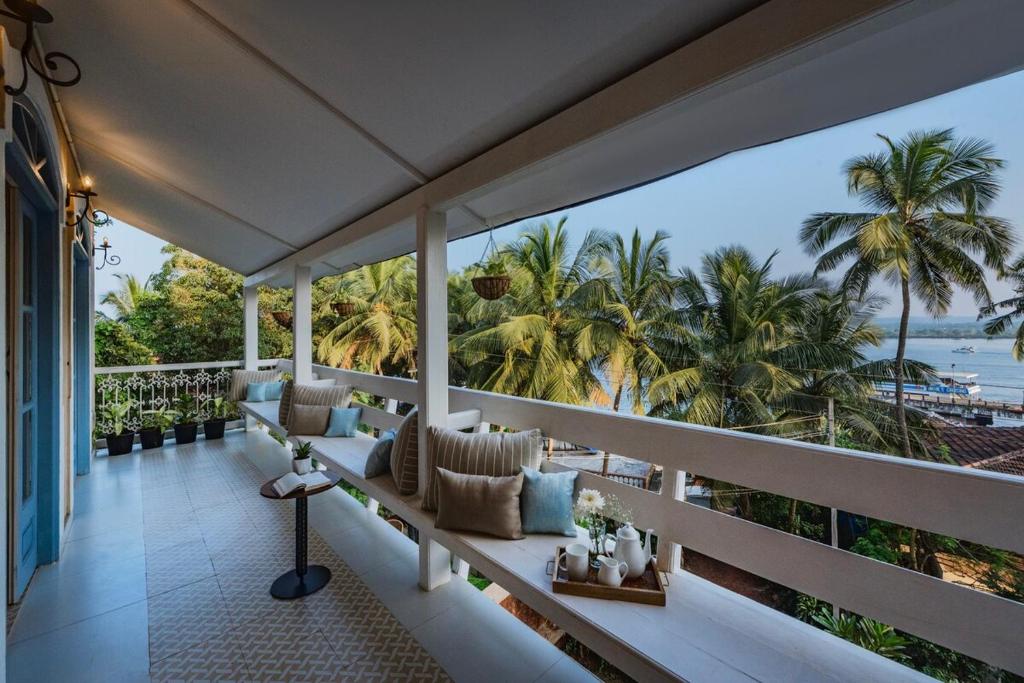 a balcony with a view of the ocean and palm trees at SaffronStays RiverSong Britona in Ribandar