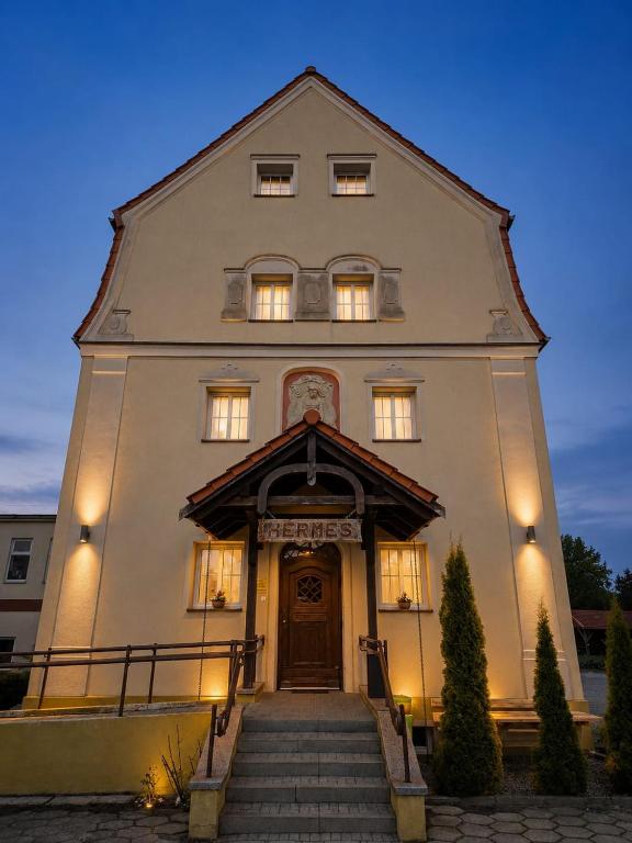 a large white building with stairs leading to the door at Młyn Warmiński -Hotelik Hermes in Pieniężno