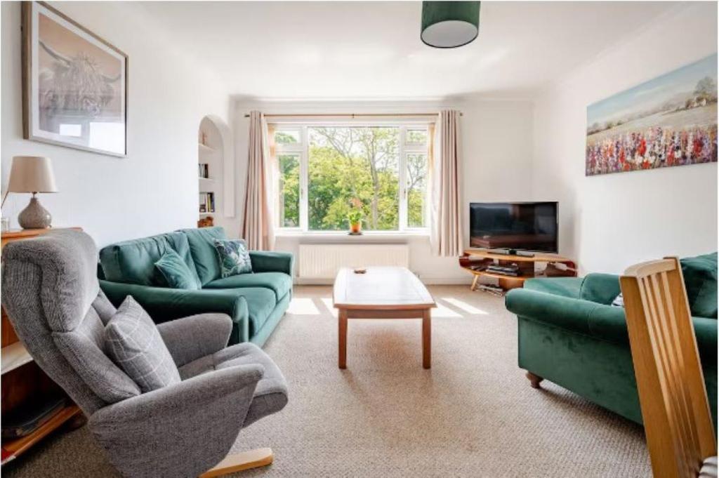 a living room with green couches and a tv at The Waterside Apartment 6 in Largs