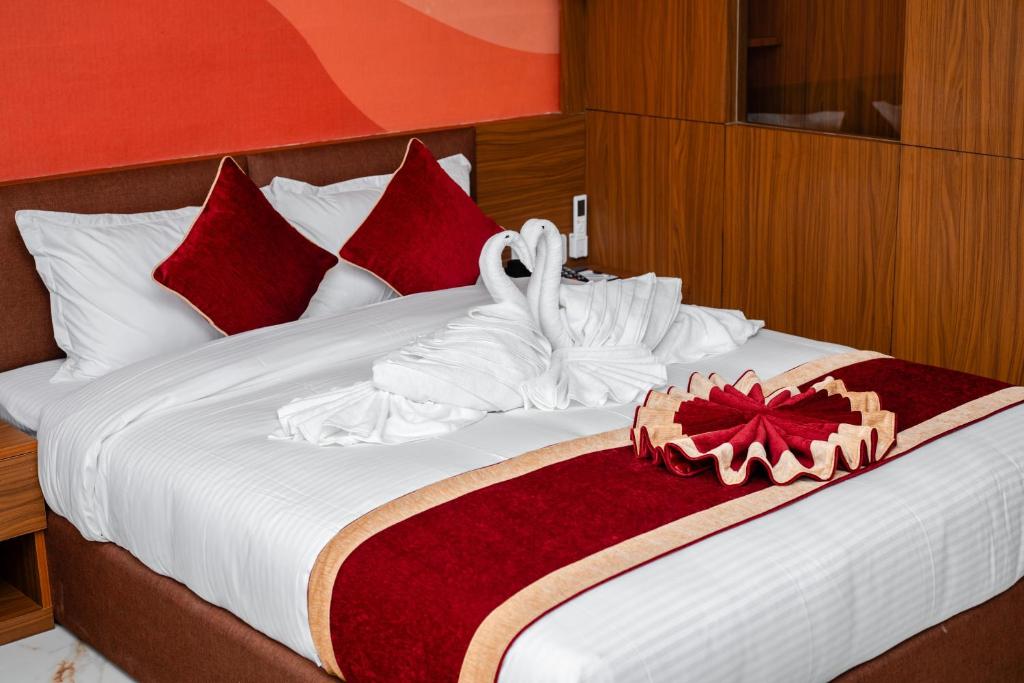 a large bed with red and white pillows at GermanHomesHotel in Thimi