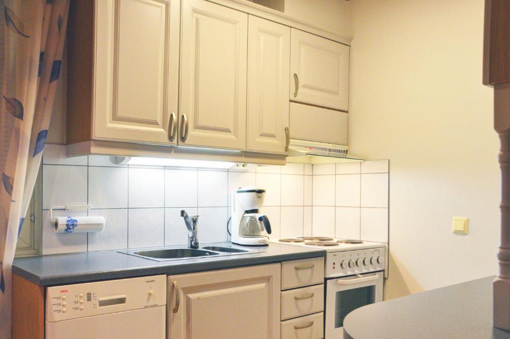a kitchen with white cabinets and a kitchen sink at Alppitalo 2 as 1 in Tahkovuori