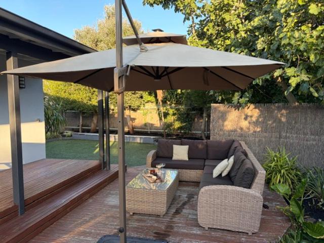 a patio with a couch and an umbrella at 10-Min Walk to Pearce Beach via Coastal Trail in Blairgowrie