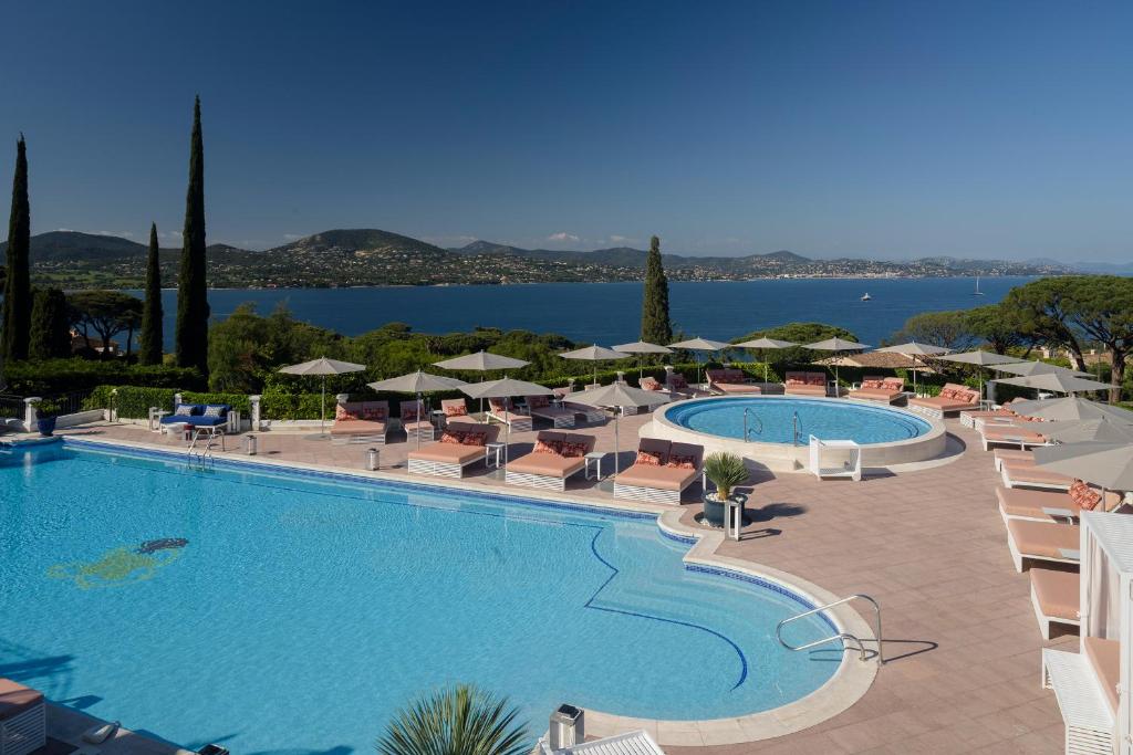 a large swimming pool with chairs and umbrellas at Althoff Hotel Villa Belrose in Saint-Tropez