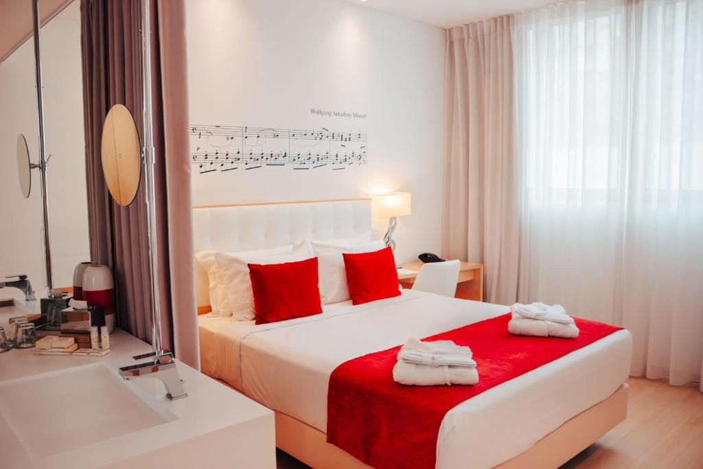 a bedroom with a bed with red pillows and a sink at Hotel da Música in Porto