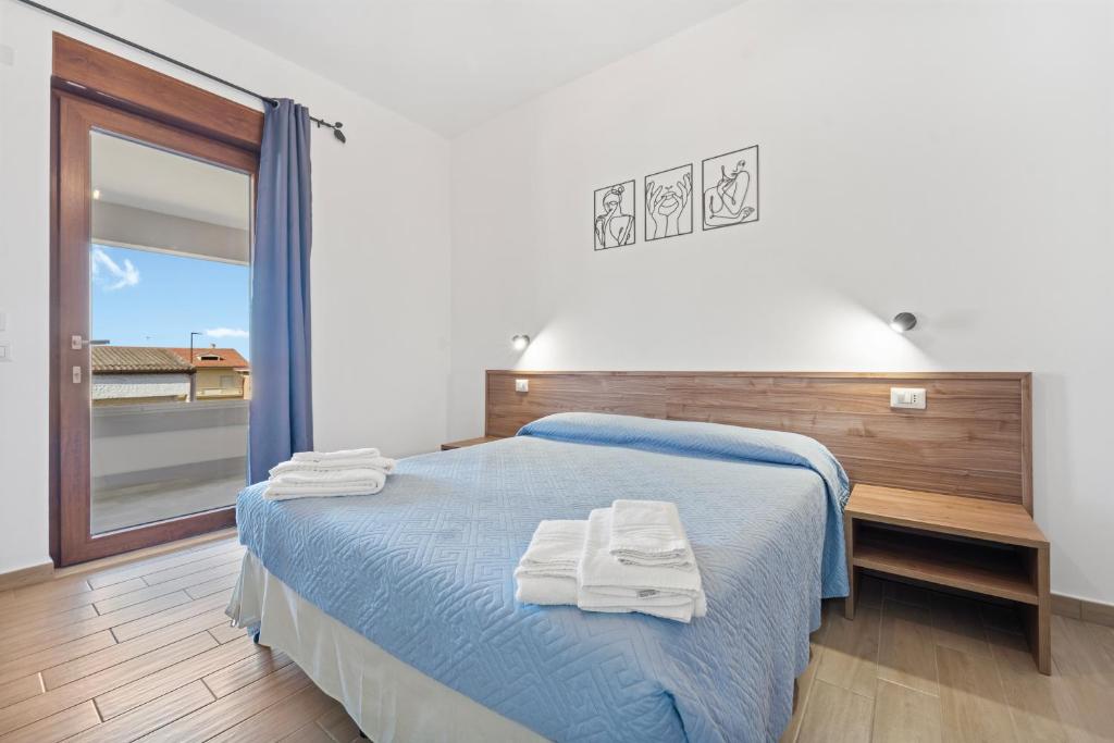 a bedroom with a blue bed with towels on it at CLASS ROOMS AFFITTACAMERE con bagno privato , vicino alle DUNE di PORTO PINO in SantʼAnna Arresi