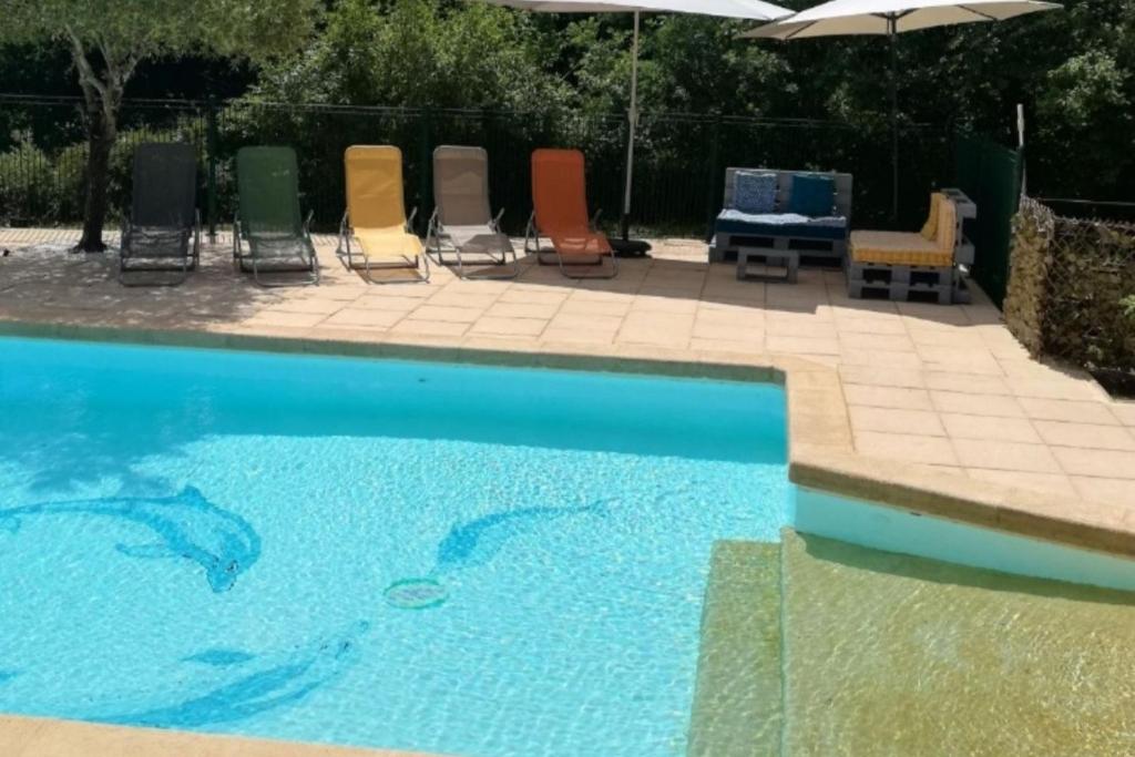 a pool with chairs and a table and an umbrella at Le roqual in Carsac-Aillac