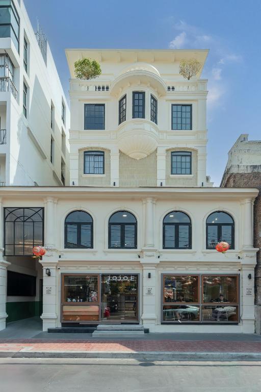 a large white building with a store front at Merchant's Gate Songwat in Bangkok