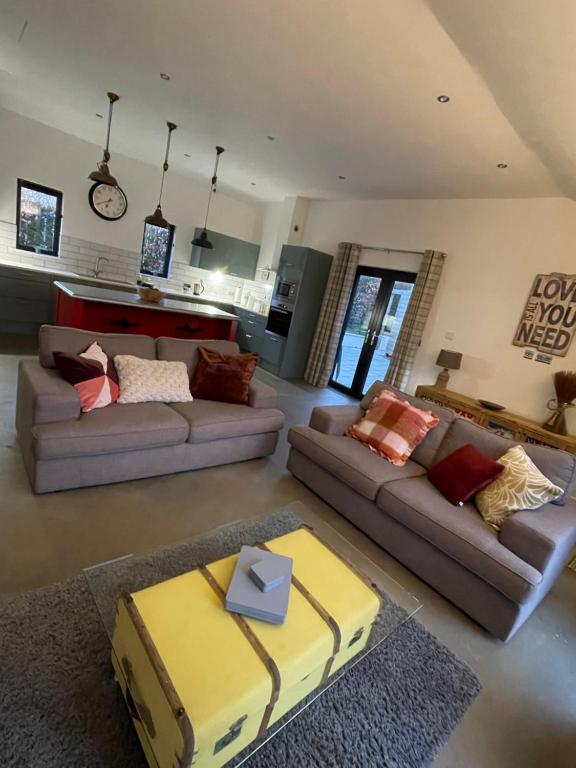 a living room with two couches and a kitchen at Umber, Gallery Cottages, Devon in West Putford