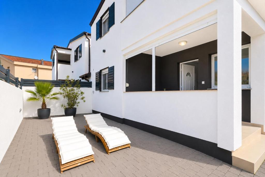 a pair of lounge chairs on the patio of a house at Apartments ROSINI, 300m from the beach with shared tavern and bikes, Nin in Nin