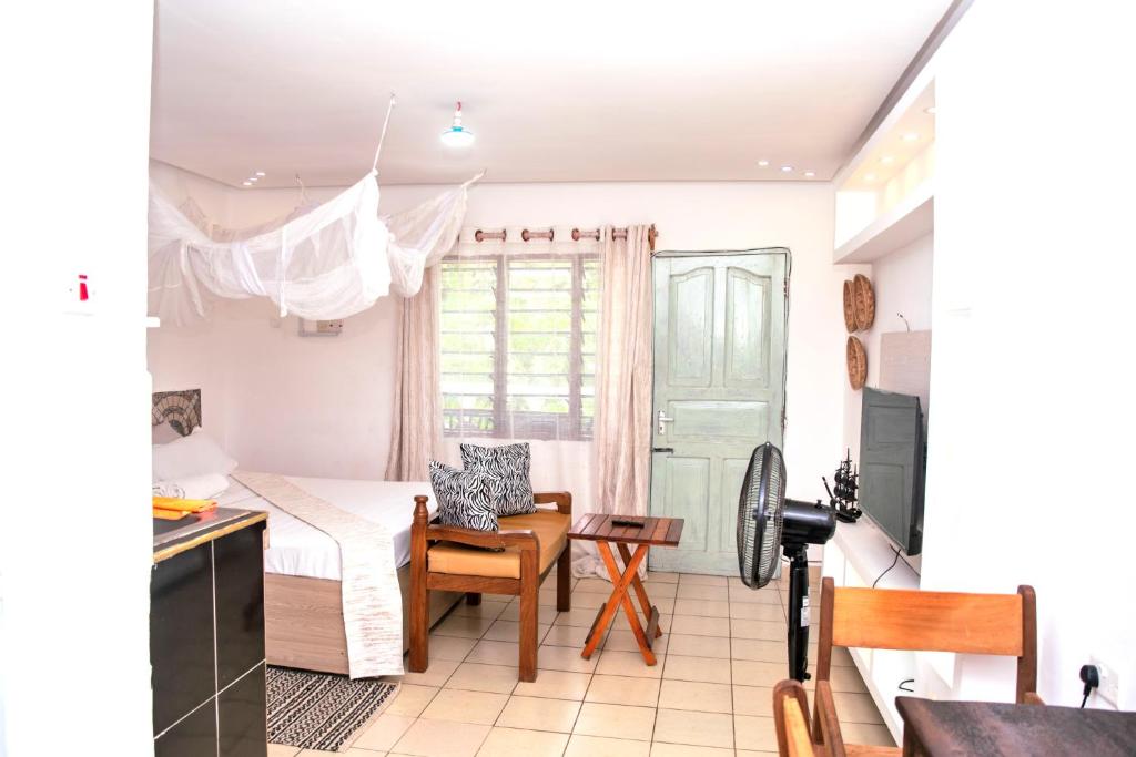 a bedroom with a bed and a desk and a table at Angie's Cozy Studio Diani Beach in Ukunda