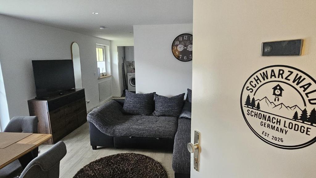 a living room with a couch and a sign on the door at Schwarzwald Lodge Schonach in Schonach