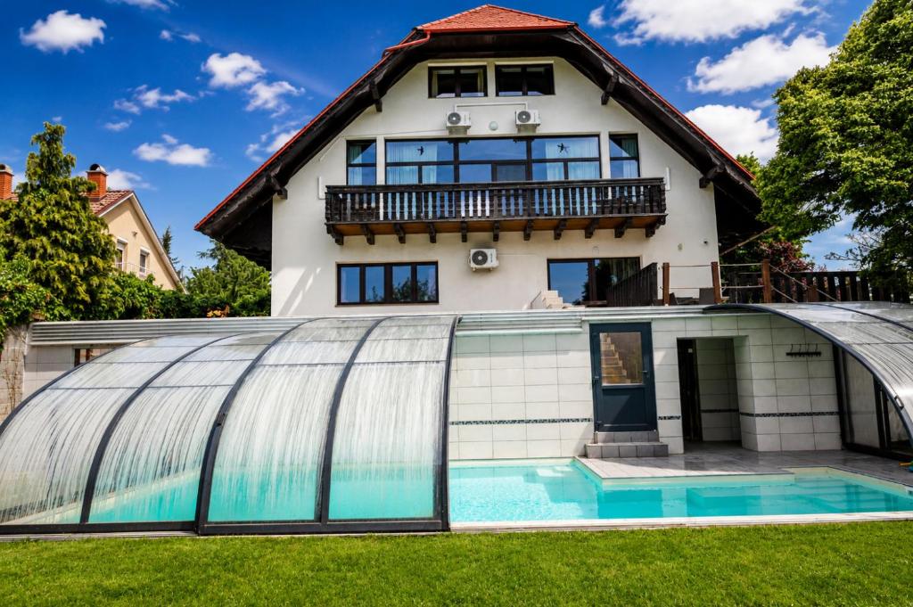 a house with a swimming pool in front of a building at Határtalan Vendégház in Pilisszentiván