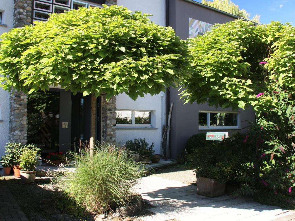 un edificio con alberi e piante di fronte ad esso di Ferienwohnungen PANO a Friedrichshafen