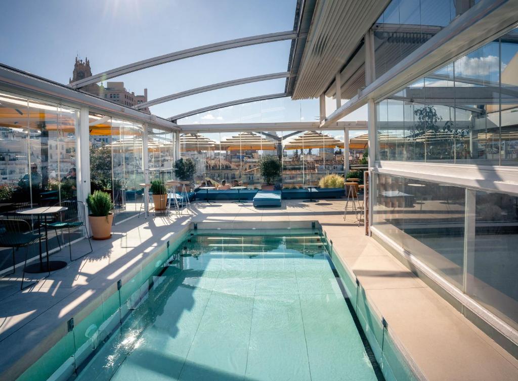 an indoor swimming pool in a building with glass walls at Room Mate Oscar, Madrid in Madrid