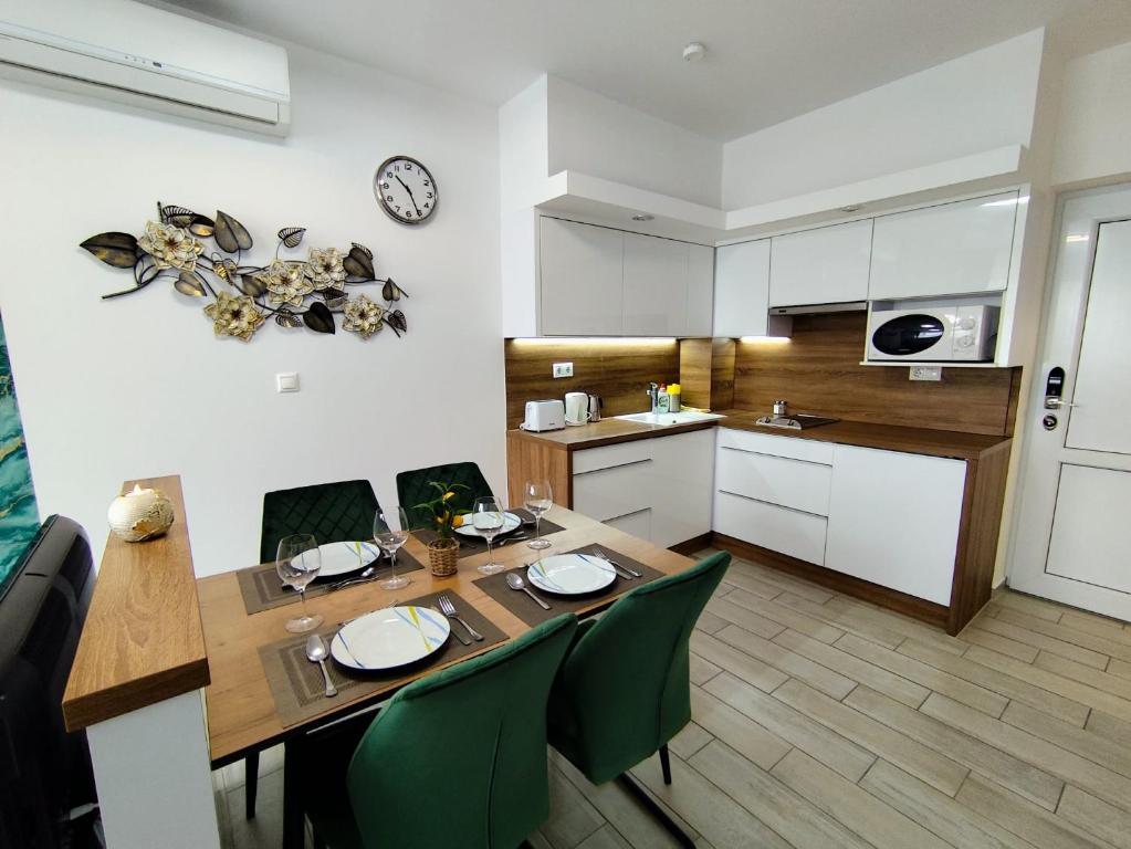 a kitchen and dining room with a table and green chairs at Rubin Verde Residence in Sárvár